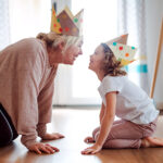 small girl with grandparent wearing crowns and playing