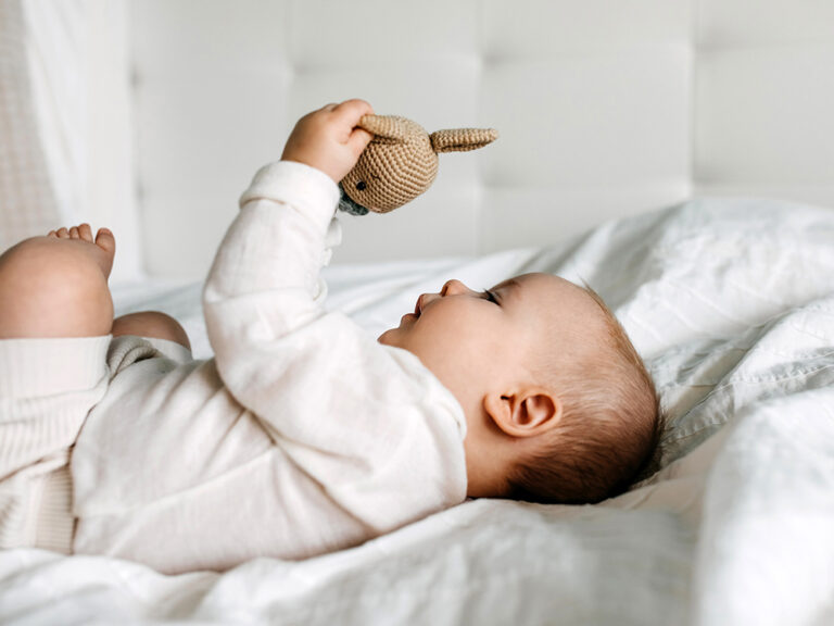 five month old baby with crocheted rattle