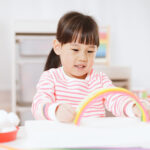 young girl with pipe cleaners making rainbow arch