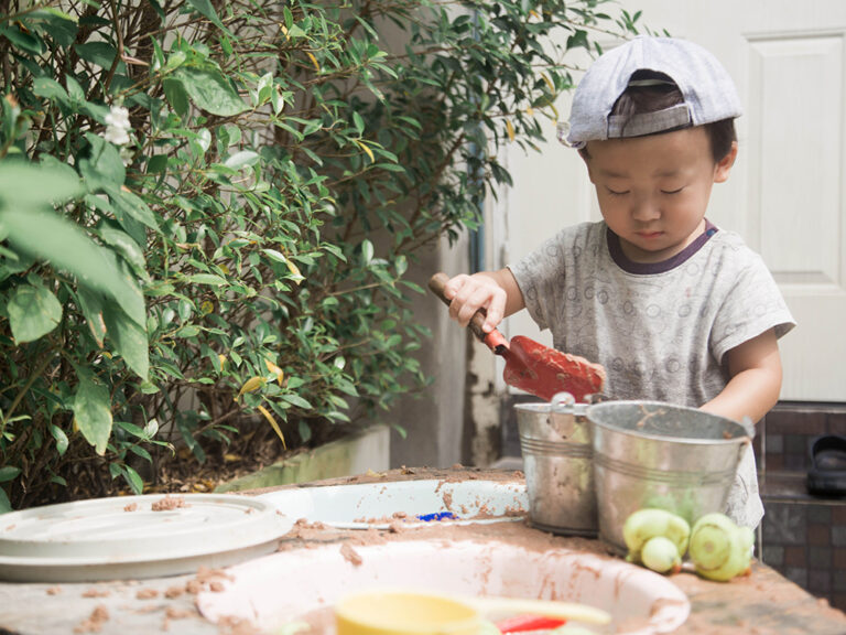 toddler playing in mud kitchen